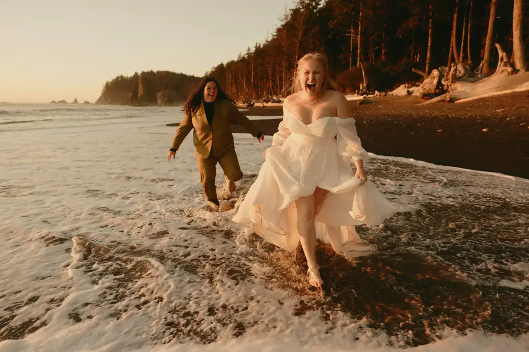 wedding day couple running on beach joyfully