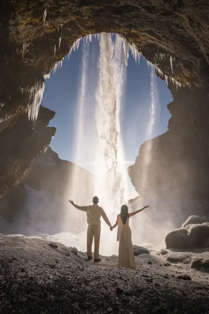 couple holding hands underneath a waterfall