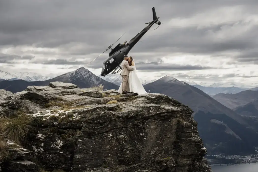 elopement couple on mountain with helicopter flying overhead