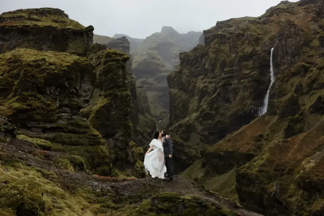 Elopement couple in Iceland's green mountains with a waterfall